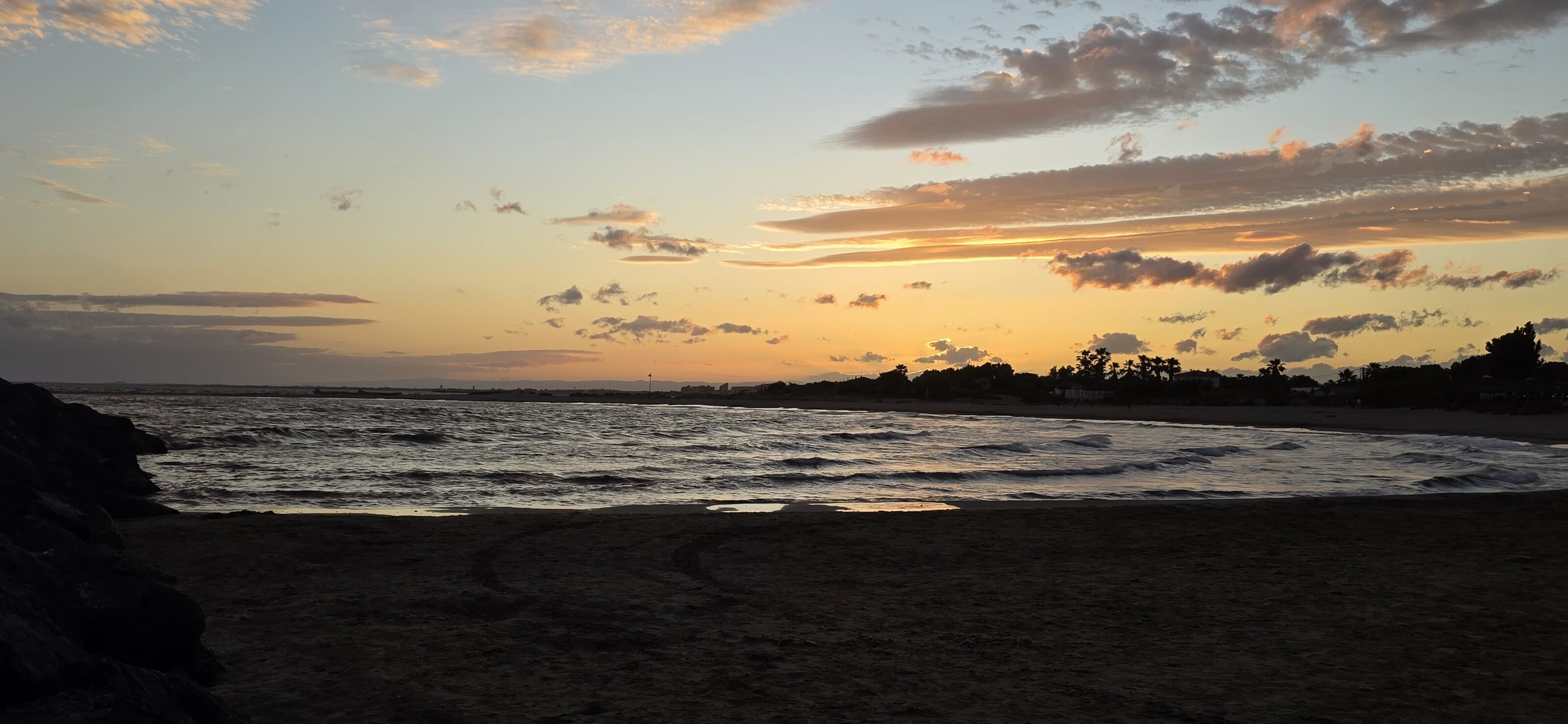 Coucher de soleil sur la plage du Cap d'Agde, la mer et le sable au premier plan