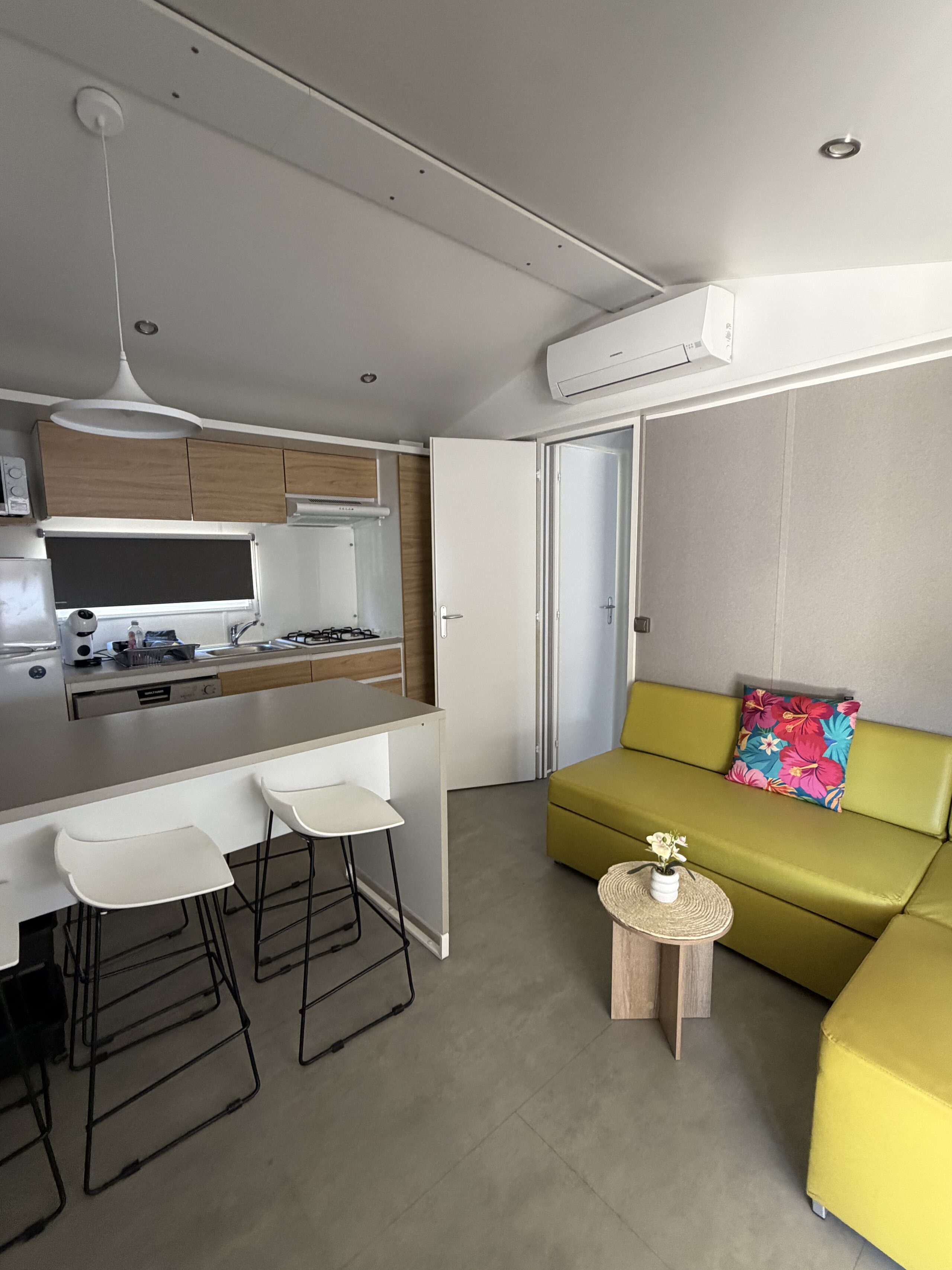 Le salon du mobil-home, avec sa banquette d'angle et la baie vers la terrasse