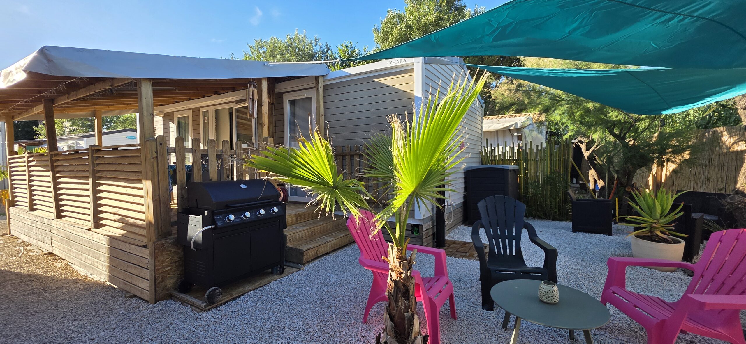 La terrasse et le salon de jardin du mobil-home, sous les voiles d'ombrage turquoise